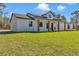 Stunning white farmhouse with black trim, wooden columns, and covered porch surrounded by a lush green lawn at 8827 Sw 137Th Ct, Dunnellon, FL 34432