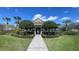 Landscaped clubhouse featuring manicured shrubs, palm trees, and a sidewalk leading to the entrance at 1727 Saffron Plum Ln, Orlando, FL 32828