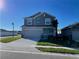 Two-story home with a two-car garage, complemented by a lush green lawn and a charming exterior at 247 Villavista Ct, Davenport, FL 33896