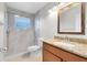 Bathroom featuring a large mirror, vanity lighting, tiled walk in shower with glass door at 9517 Brackin St, Orlando, FL 32825