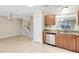 Practical kitchen with tile floor, stainless steel dishwasher and serving hatch to the living room at 9517 Brackin St, Orlando, FL 32825