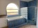 Blue bathroom with bathtub, glass block window and tiled shower at 2708 Smithfield Dr, Orlando, FL 32837