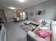 A modern living room features a white leather sofa, decorative pillows, and open-concept dining space with plenty of natural light at 881 Orchid Grove Blvd, Davenport, FL 33837