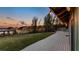Backyard with large grassy lawn, a deck with string lights, and scenic lake views at sunset at 647 Ridgewood Dr, Windermere, FL 34786
