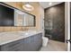 Modern bathroom with a stone countertop vanity, stand up shower with dark accent tiling and unique light fixture at 1340 Susannah Blvd, Orlando, FL 32803
