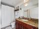 Well-lit bathroom with granite countertop, cherry wood cabinet, and shower with white curtain at 155 S Court Ave # 1602, Orlando, FL 32801