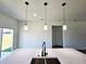 Modern kitchen island with pendant lighting, stainless steel sink, and matte black faucet at 4655 Sw 139Th Ln, Ocala, FL 34473