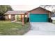 Brick ranch house with teal garage door, well-manicured lawn, and walkway at 3021 Norvell Ct, Deltona, FL 32738