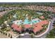 Wide aerial view of a community center featuring a large pool, splash pad, and tennis court amidst lush landscaping at 5303 Wildwood Way, Davenport, FL 33837