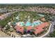Aerial view of a community center featuring a large pool, splash pad, and tennis court amidst lush landscaping at 5303 Wildwood Way, Davenport, FL 33837