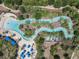 Aerial shot of a lazy river with people floating, surrounded by palm trees, lounge chairs, and blue umbrellas at 5303 Wildwood Way, Davenport, FL 33837