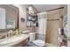 Neutral bathroom featuring a shower, toilet, sink with granite counter, and black iron shelving at 405 Mallard Ln, Kissimmee, FL 34759