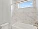 Bathtub with white tile surround, chrome fixtures, and a window that provides natural light at 10852 Mobberley Cir, Orlando, FL 32832