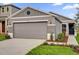 Charming one-story home with a gray exterior, a two-car garage, and landscaped front yard at 219 Ash Way, Auburndale, FL 33823