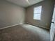 This carpeted bedroom provides neutral walls, a bright window, and a white door at 5298 Teirgarten St, St Cloud, FL 34771