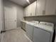 Functional laundry room with washer, dryer, sink, cabinets, and wood-look flooring at 5298 Teirgarten St, St Cloud, FL 34771