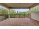 A covered outdoor balcony with a brick floor and black railing overlooks a lush green landscape at 13007 Bromborough Dr, Orlando, FL 32832