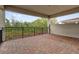 A covered outdoor patio with a brick floor and black railing overlooks a lush green landscape at 13007 Bromborough Dr, Orlando, FL 32832