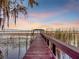Scenic dock with charming covered area extending into a serene lake at sunset at 6320 Rocky Point Rd, Lake Wales, FL 33898