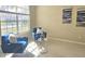 Comfortable sitting room featuring two blue chairs, side table, artwork, and natural light through the window at 12859 Enclave Dr, Orlando, FL 32837