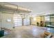 Spacious two-car garage with white doors, concrete floor, exposed ceiling fixtures, shelving and a large storage rack at 7200 Grace Rd, Orlando, FL 32819