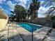 Backyard view of a beautiful fenced pool, surrounded by lush trees and blue skies at 4617 Frisco Cir, Orlando, FL 32808