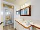 Well-lit bathroom featuring a sink with vanity, large framed mirror, and doorway into the shower at 6353 River Rd, New Smyrna Beach, FL 32169