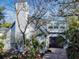 Front exterior featuring a chimney, new windows, garage door, and lush tropical landscaping at 6353 River Rd, New Smyrna Beach, FL 32169