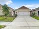 New single-story home with a two-car garage, simple landscaping, and a wide driveway under a blue sky at 791 Chinoy Rd, Davenport, FL 33837
