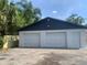 Two-car garage with white doors and dark gray roof with a side door at 1625 Normandy Way, Leesburg, FL 34748