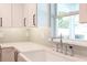 Bright kitchen features a white farmhouse sink, white cabinets, and mosaic tile backsplash at 2260 Mulbry Dr, Winter Park, FL 32789