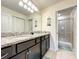 Bathroom featuring double sinks, granite countertops, dark cabinets and a glass enclosed shower at 826 Paradise Dr, Davenport, FL 33897