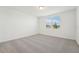 Bright bedroom featuring neutral carpeting, a window overlooking the neighborhood, and white walls at 1124 Griffon Ave, Lake Alfred, FL 33850