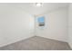 Bright bedroom with neutral carpeting, white walls, and a window view of the neighborhood at 1124 Griffon Ave, Lake Alfred, FL 33850