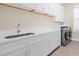 Well-equipped laundry room with white cabinets, ample counter space, stainless steel sink, and modern appliances at 12608 Ne 49Th Dr, Oxford, FL 34484