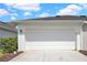 Two-car garage with driveway, manicured shrubs, and neutral exterior paint at 14480 Chinese Elm Dr, Orlando, FL 32828