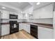 Modern kitchen with white cabinets, black appliances, and wood-look flooring at 5533 Satel Dr, Orlando, FL 32810