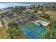 Scenic aerial view showcasing community amenities: pool, tennis/pickleball, and basketball courts near a serene lake at 10157 Spring Lake Dr, Clermont, FL 34711