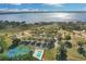 Stunning aerial view of lakefront property featuring a pool, tennis courts, and lush landscaping at 10157 Spring Lake Dr, Clermont, FL 34711