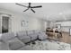 Open-concept living room with modern gray sofa, ceiling fan, and kitchen with white cabinetry at 10157 Spring Lake Dr, Clermont, FL 34711