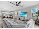 Open-concept living room features a large sectional sofa, a modern ceiling fan, and an entertainment center with a flat-screen TV at 10157 Spring Lake Dr, Clermont, FL 34711
