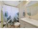 Bright bathroom with a large mirror, white vanity, and a shower-tub combination with a leaf-patterned curtain at 27601 Country Stone Ct, Leesburg, FL 34748