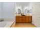 Bathroom featuring a double sink vanity with wood cabinetry, tile flooring, and a separate bathtub at 27601 Country Stone Ct, Leesburg, FL 34748