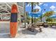 Poolside dining area with wooden picnic tables, surfboard signage, and shady umbrellas at 7770 Sandy Ridge Dr # 114, Reunion, FL 34747
