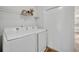 A well-lit laundry room featuring a modern white washer and dryer set, with storage shelving, and wood look flooring at 1445 Creekside Cir, Winter Springs, FL 32708