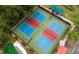 Aerial view of two vibrant pickleball courts with blue and red zones, surrounded by lush greenery at 7652 Whisper Way # 104, Reunion, FL 34747