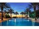 Stunning community pool lined with palm trees and lounge chairs, perfect for relaxing and enjoying the sunset at 7652 Whisper Way # 104, Reunion, FL 34747