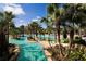 Resort-style pool with palm trees, clear blue water, and tropical landscaping for relaxation and recreation at 7652 Whisper Way # 104, Reunion, FL 34747
