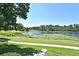 Panoramic lake view from the yard, bordered by lush trees and vibrant green grass at 77 Spring Glen Dr, Debary, FL 32713