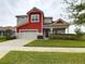 Two-story red and beige house with a gray paved driveway and landscaped lawn at 2506 Volunteer Ave, Kissimmee, FL 34744